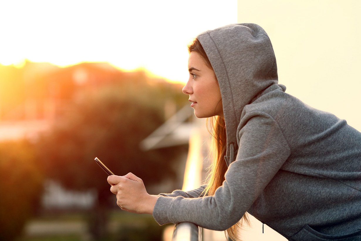 a woman in a gray hoodie looking at the unset
