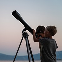 two children looking through a telescope