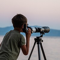 a boy looking through a telescope